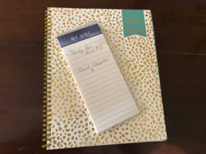 A photograph of a spiral bound notebook with a list on top.