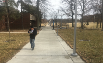 A person walks along a sidewalk on the UCBA campus.