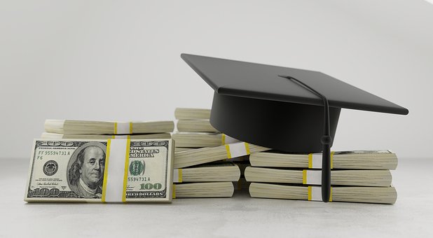 Graduation cap on top of 100 dollar bills.